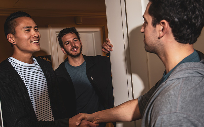 a handshake between two men at a doorway